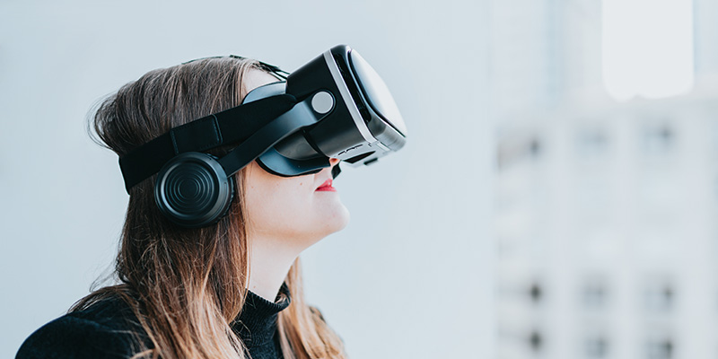 Was ist eigentlich ein Metaverse? Bild von Frau mit VR-Headset vor weissem Hintergrund