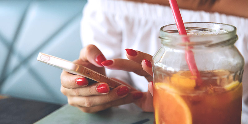 WLAN in den Ferien: Frau am Handy in Café